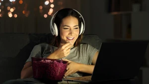 Woman looking at a laptop eating popcorn