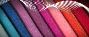 rolls of fabric stacked on top of each other in shades of pink, red, purple, and teal