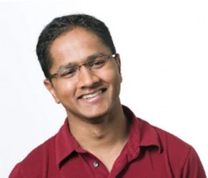 man smiling at camera in a red polo shirt and glasses