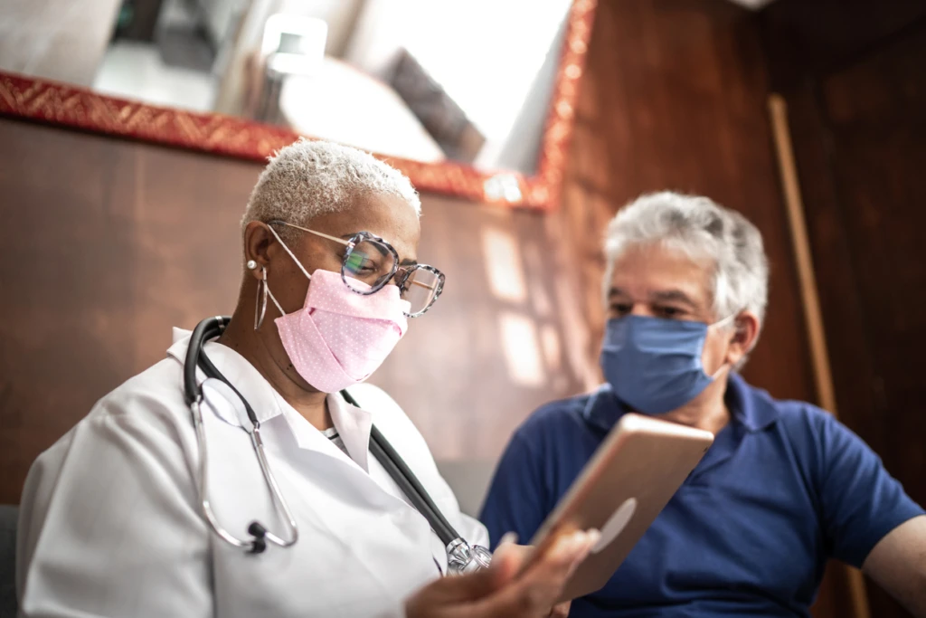 Doctor talking to senior male patient in a home visit