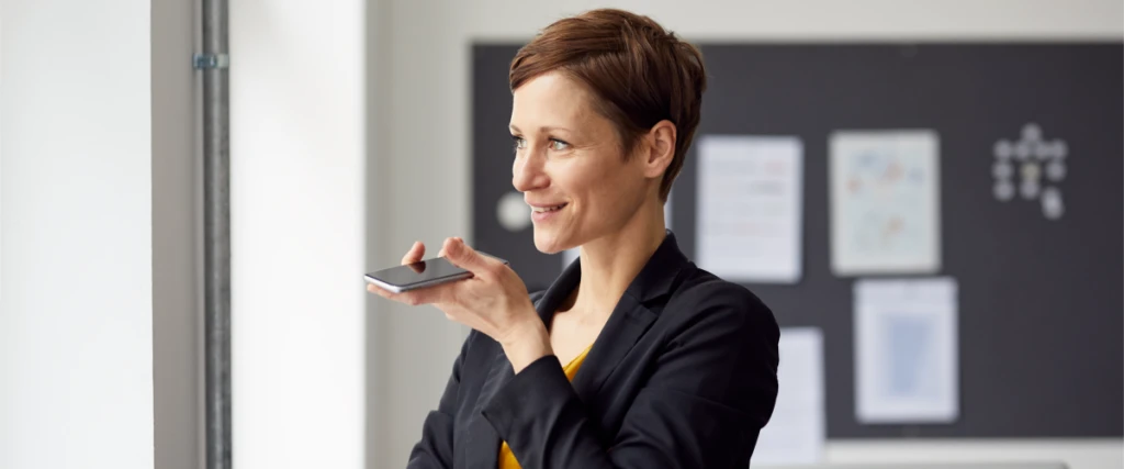 A person looking out the window smiling and talking into a mobile phone.