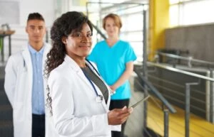 A healthcare professional holding a tablet looking at the camera.