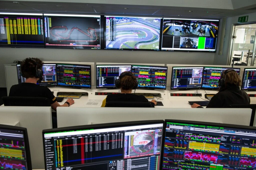 A team of technicians examine performance test results in racing simulator of Formula One manufacturing plant.