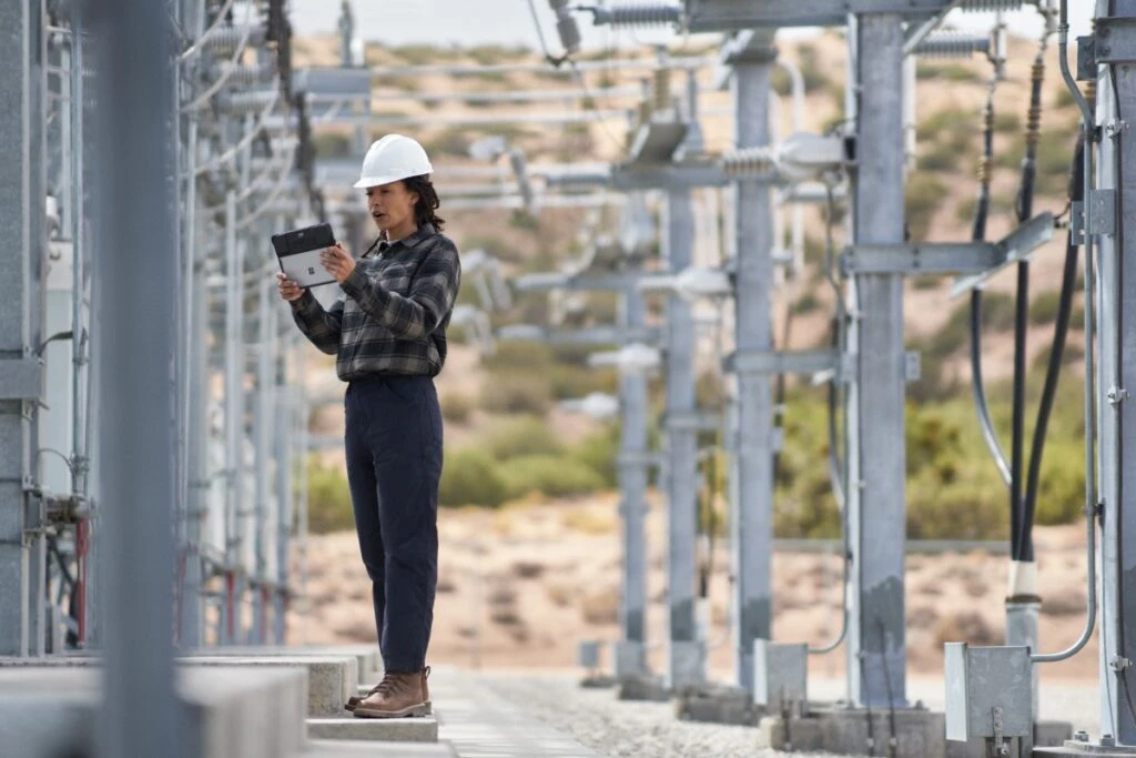 Field engineer inspects electrical substation on a wind farm using remote assist with a Surface tablet