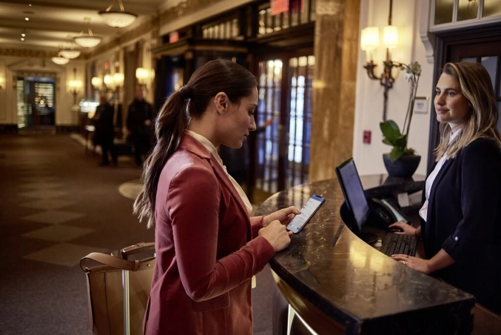 Female small business executive checking in at a hotel using Samsung Galaxy; mobile device; smartphone; remote.