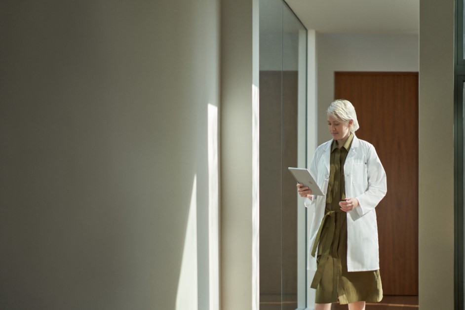 Doctor walking to office to take a telehealth video call via a tablet.