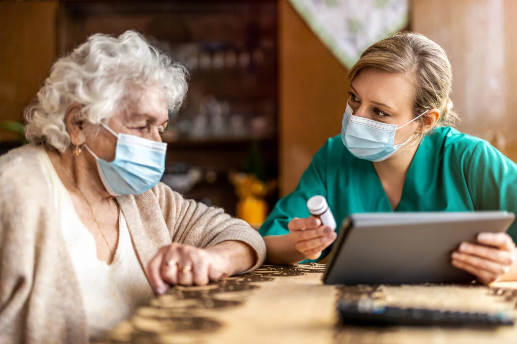 Home caregiver helping senior woman with medication