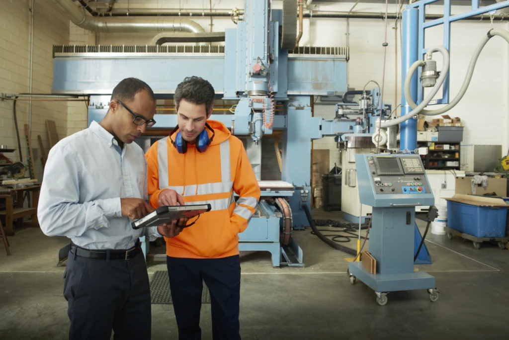 Manufacturing engineers interacting, tablet in hand.