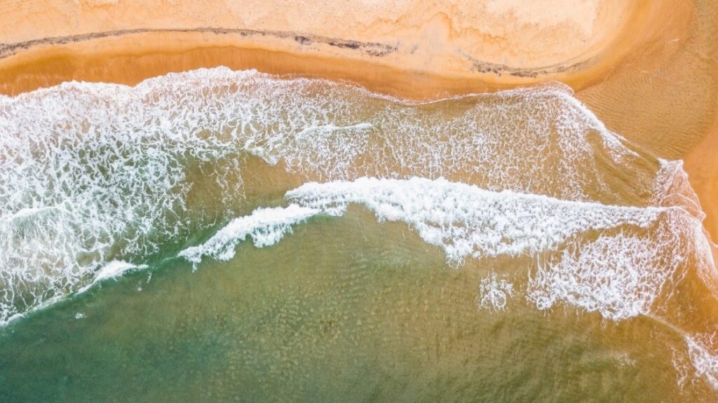 Waves of ocean surf washing onto a beach.