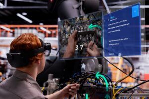 Automotive manufacturing worker in a factory uses a Guide wearing the HoloLens 2 to service a robotic arm wiring system with mixed reality instructions.