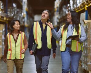 Warehouse workers walking through the aisle; manager reviewing and sharing data real time to make intelligent decisions powered by Azure.
