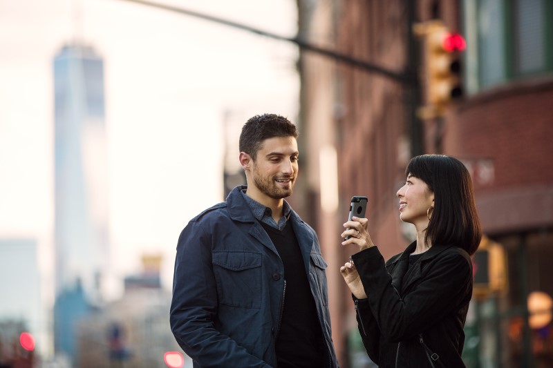 Female with phone with male on urban street.