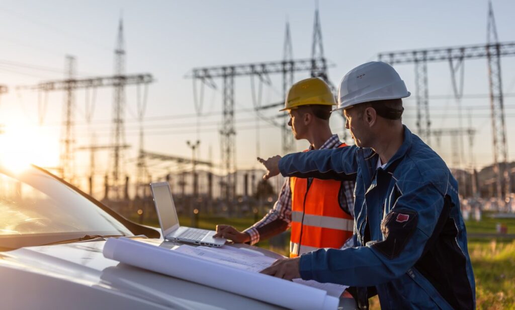 A group of men in hardhats and vests looking at a laptop