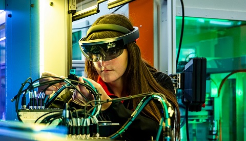 Eine Frau mit einer HoloLens2 arbeitet in einem technischen Labor.
