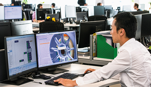 Man working in an office with several screens on his desk