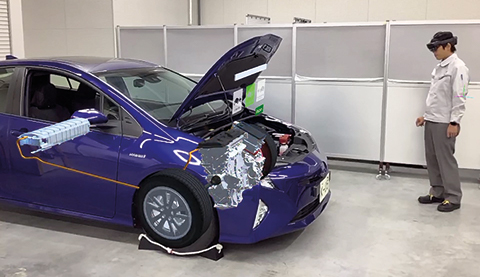Man standing in front of a blue car is working with HoloLens