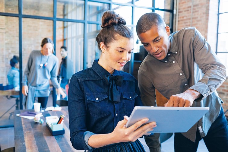 Zwei Menschen schauen interessiert in ein tablet