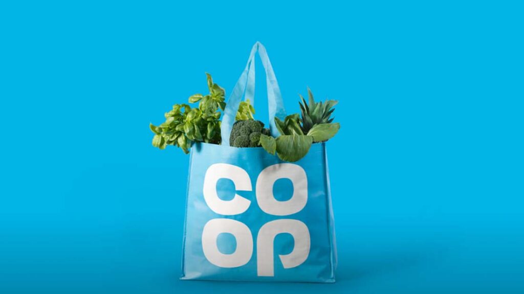 Blaue Coop Einkaufstüte mit grünen Gemüse. 