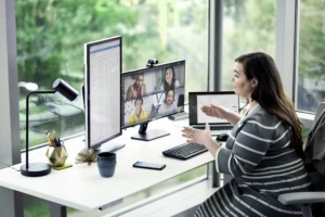 Female enterprise employee working at desk with multiple devices, talking on Teams