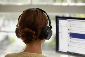 Photograph of female employee wearing Surface Headphones 2 working in Teams