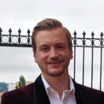 George Hackford, a man in a business suit and light hair smiling at the camera.