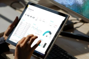 A close up of a data dashboard on a Surface device with a person hands interacting with the screen.