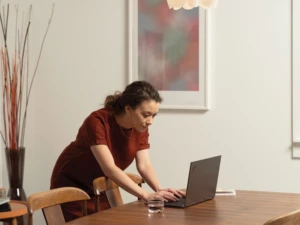 A woman at her diningroom table looking at her computer