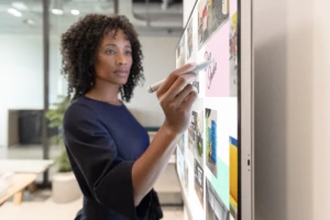 Woman executive working on Surface Hub 2S in Whiteboard with Surface Hub 2 Pen in a hybrid working environment