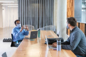 Two men in a meeting room wearing masks in a workplace with a data-driven culture.