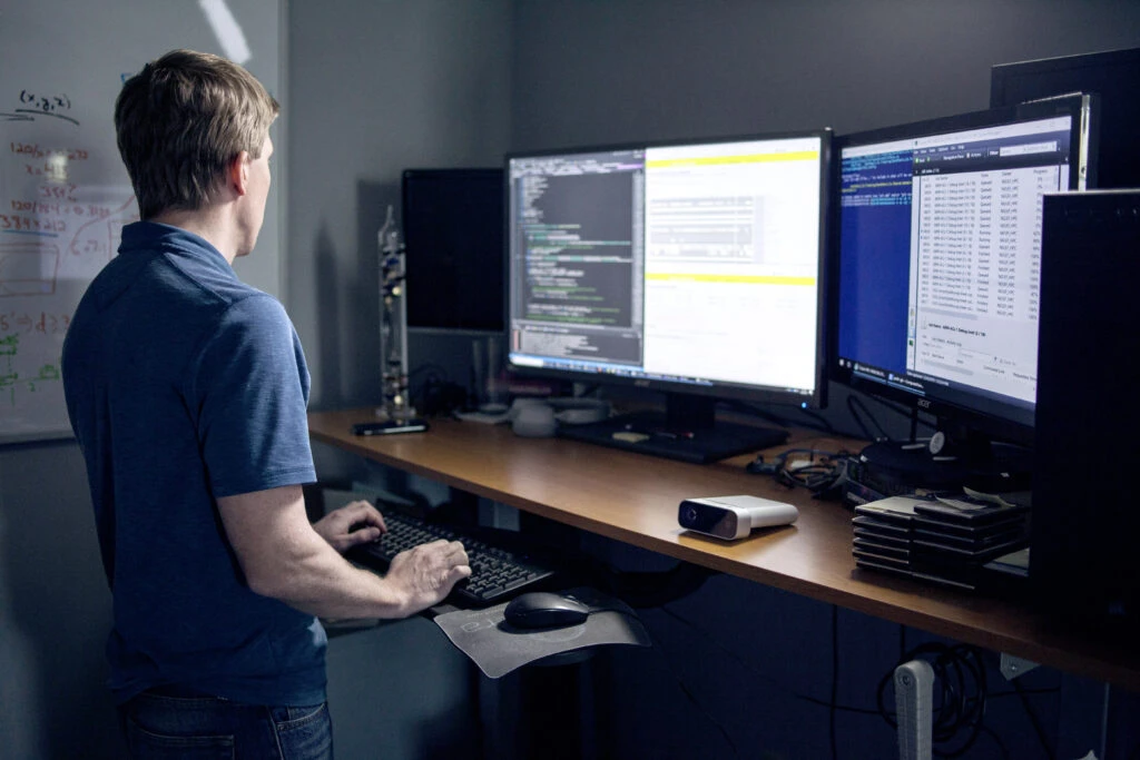 A male developer behind a standing desk coding