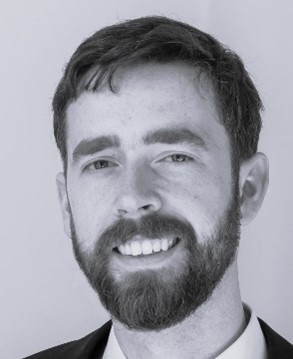 Photo of a person with short hair and a beard smiling at the camera