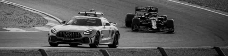 A black and white photo of an F1 car and a safety car