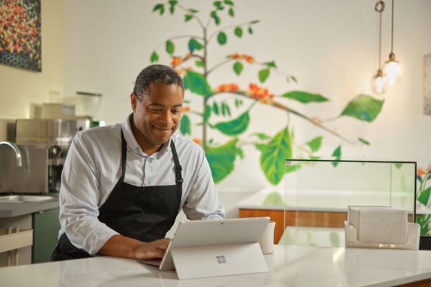 Photographie de chef debout dans une cuisine travaillant sur un appareil Surface.