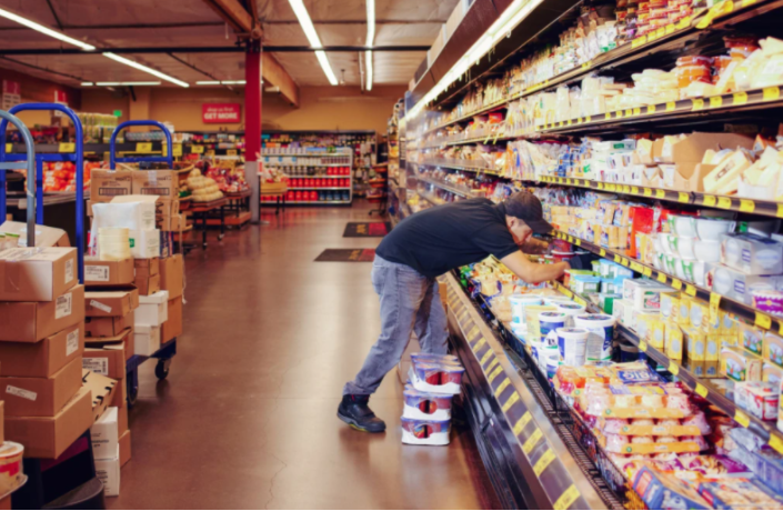 Homem trabalhando em uma prateleira de supermercado