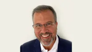 a man wearing a suit and tie smiling at the camera