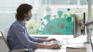 a man with a mask working on a laptop