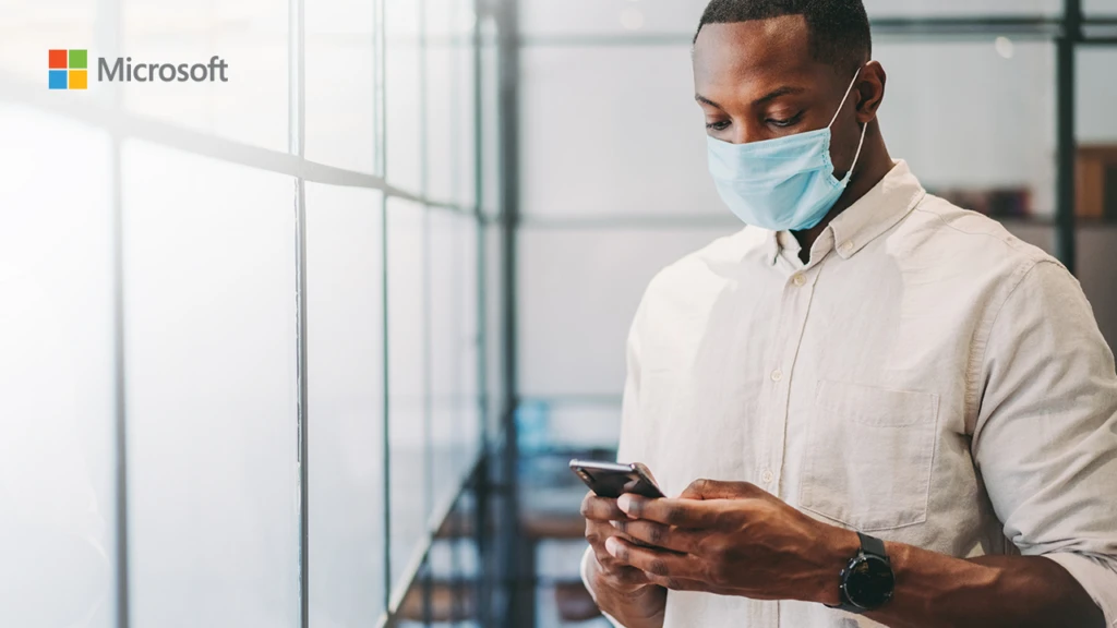 man with a face mask texting on his phone
