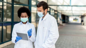 Doctors wearing face masks discussing something on the tablet