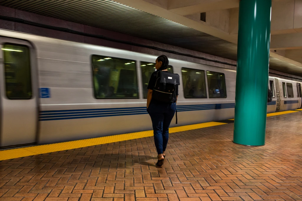 woman with a backpack waiting in the subway station in front of a moving train