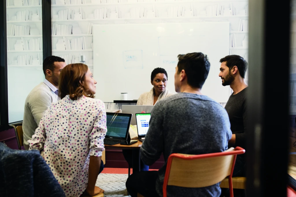 Group of 5 people in a meeting around a desk