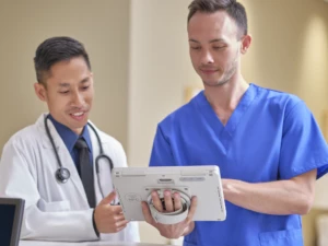 A nurse is holding a Surface Go 3 and showing a doctor something on the screen. Screen not displayed.