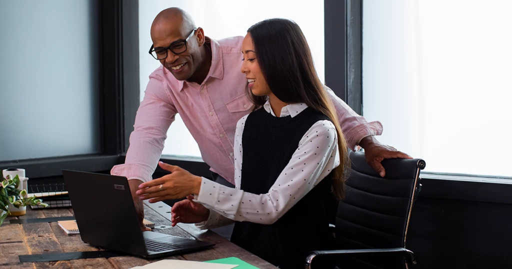Small business employees collaborating in front of a laptop on a desk.