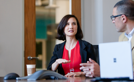 Image of a woman in a meeting, gesticulating as she speaks.