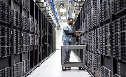 A man at work in an aisle of a datacenter.
