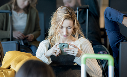 Image of a woman in an airport working on her phone.