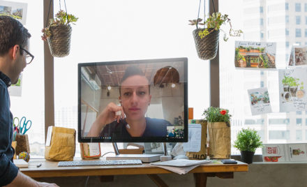 Image for: Image of a worker sitting at his desk and holding a video conference call with a coworker.