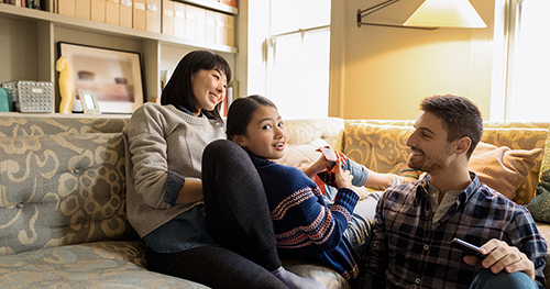 An image of a family relaxing on a couch using a laptop PC.