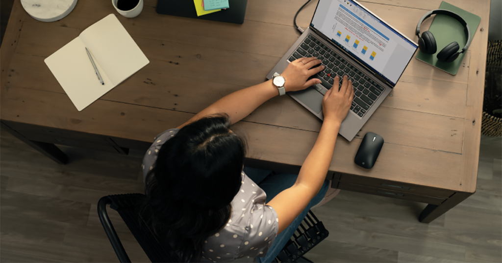 Top down photo of a person working at a desk with Lenovo ThinkPad X1 Yoga laptop and extra monitor.