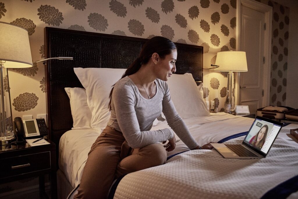 Female small business professional using Microsoft Teams in a hotel room.
