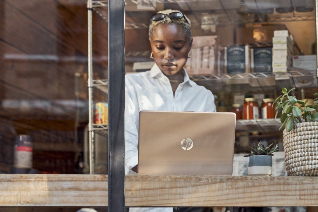 Young woman working on laptop in front of window.